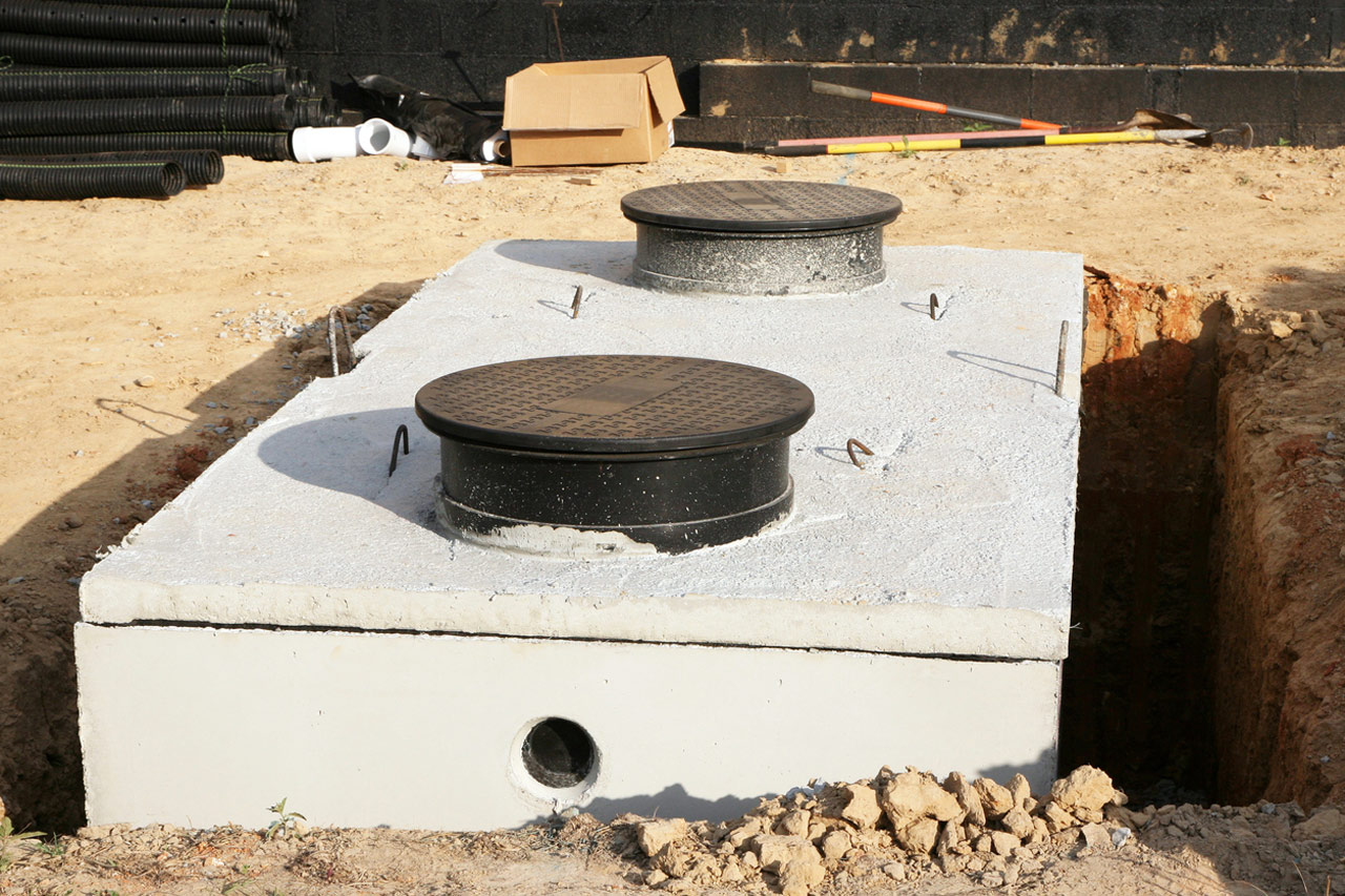 An excavated hole in the ground, cradling a newly installed septic tank resting within the cavity for efficient wastewater management